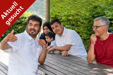 Ein Mann zeigt zwei anderen Männern und einem Kind etwas in der Ferne. Sie lächeln. 