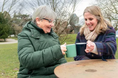 Eine Teilnehmende und eine Freiwillige von Pontesano trinken zusammen in einem Café einen Tee.