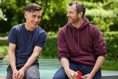 Freiwilliger bei mitten unter uns mit Begünstigtem beim Ping Pong Spielen.