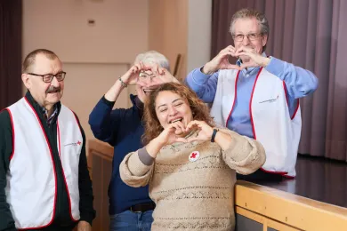 Porträtbild von vier Freiwilligen, die mit der Hand ein Herz formen