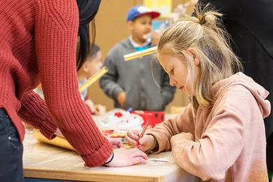Freiwillige unterstützt Kind bei den Hausaufgaben