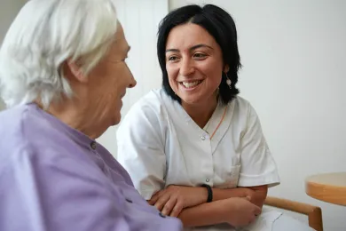 Pflegerin unterhält sich mit Patientin.