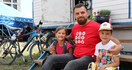 Ein Freiwilliger und zwei Ferienkinder machen Znünipause