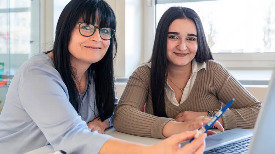 Eine Schülerin und eine Freiwillige sitzen am Tisch mit Lernmaterial