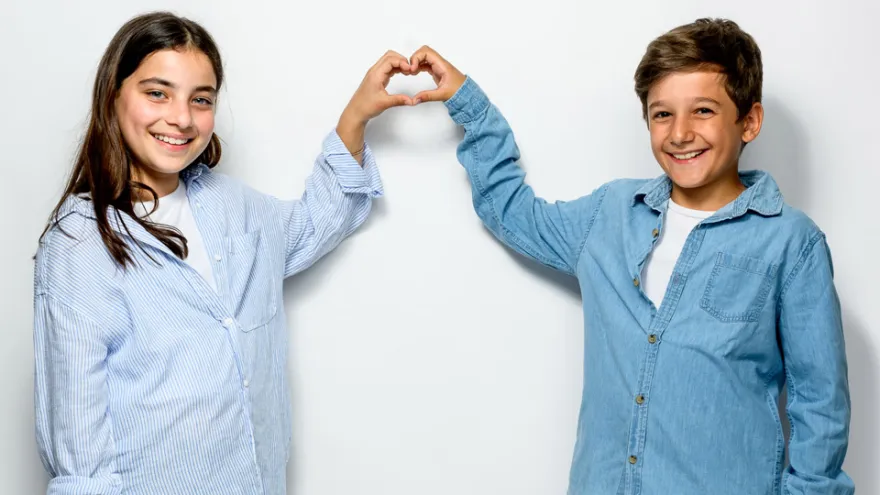 Mädchen und Junge zeigen ein Herz mit den Händen