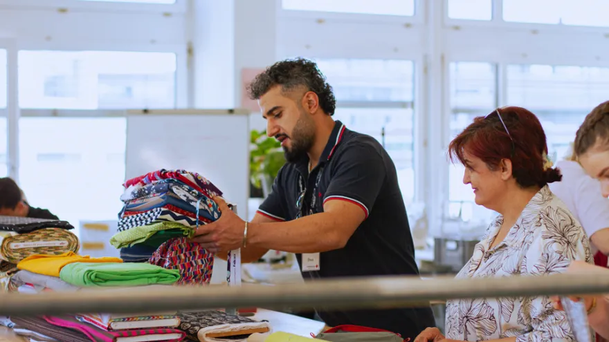 Zwei Personen bereiten Stoffe zum Nähen vor.