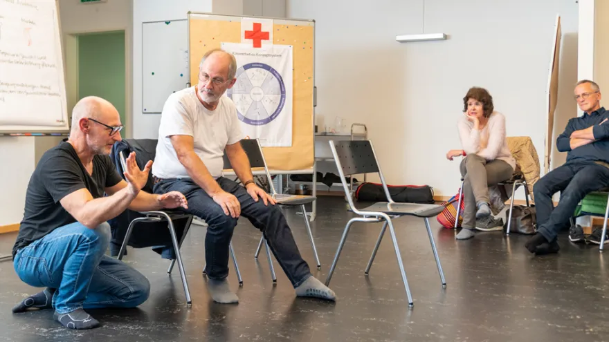 Ein Kursleiter erklärt den aufmerksamen Teilnehmenden etwas