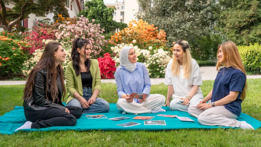 Fünf Frauen sitzen im Park und tauschen sich aus