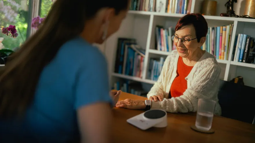 Eine Freiwillige hilft einer Seniorin beim Einrichten des Rotkreuz-Notrufs.