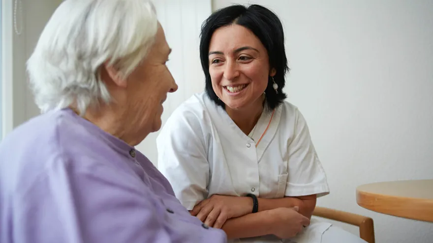 Pflegerin unterhält sich mit Patientin.