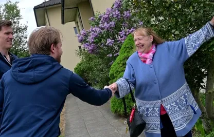 Eine Frau, die Fahrgast ist beim Zürcher Rotkreuz-Fahrdienst, wird von zwei prominenten Spielern des EHC Kloten begrüsst.